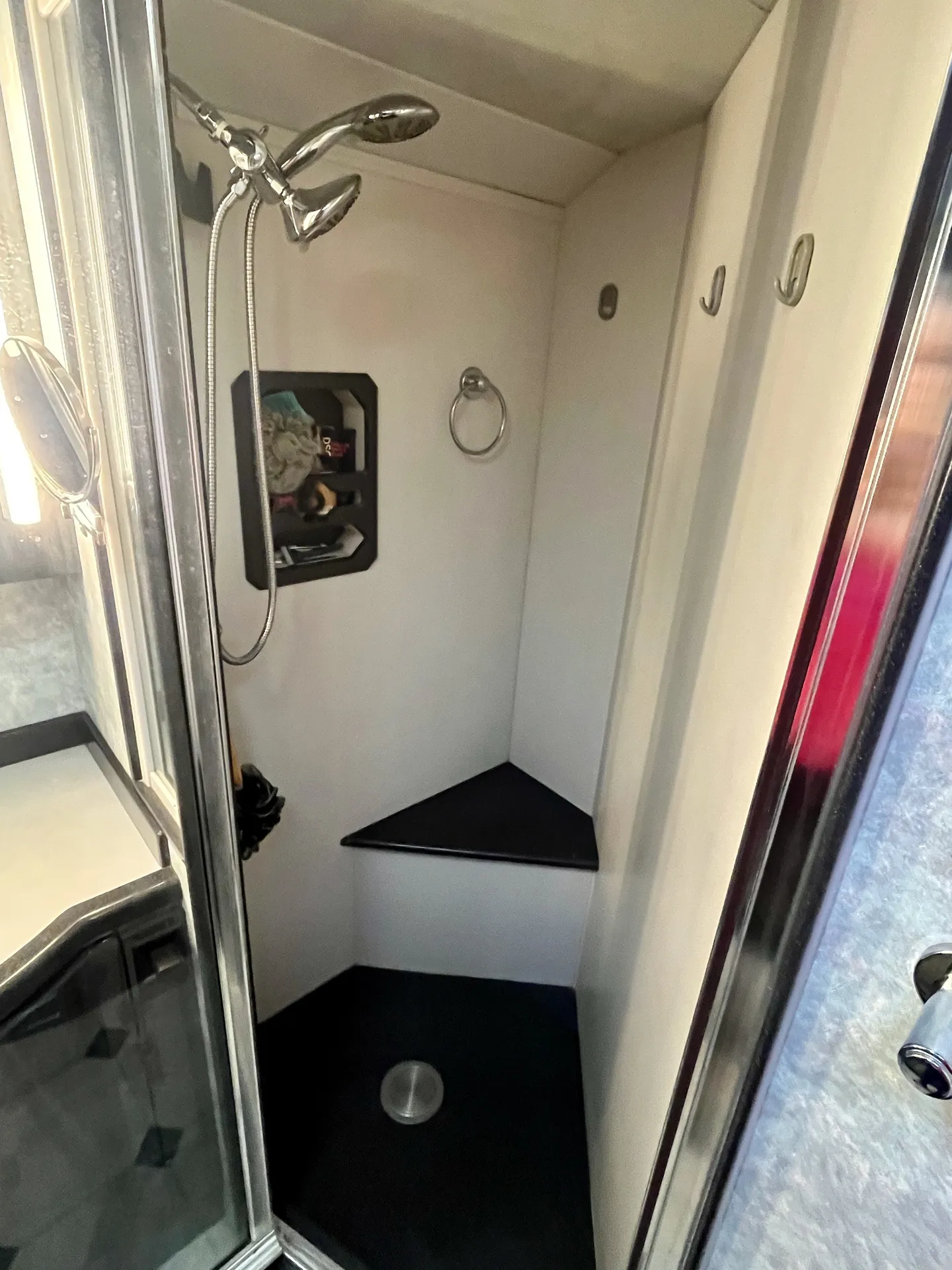 Glass-enclosed shower with chrome fixtures and corner seat