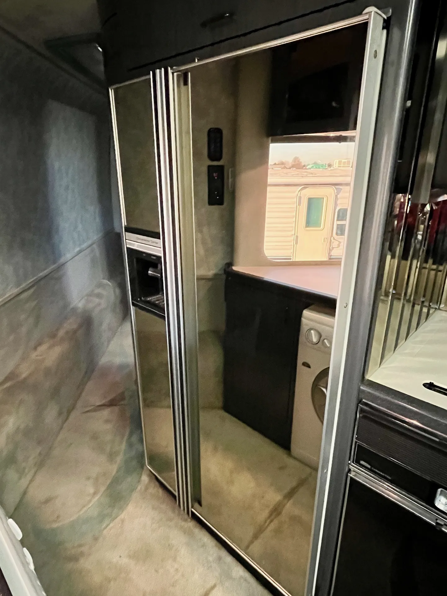 Hallway with mirrored refrigerator and laundry access